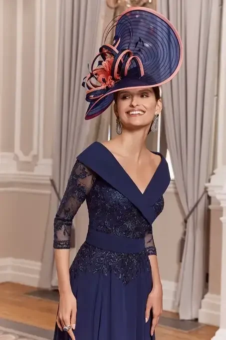 A woman in an elegant navy blue dress with lace details and a large decorative hat, walking through a lavishly decorated room with curtains and a patterned floor.