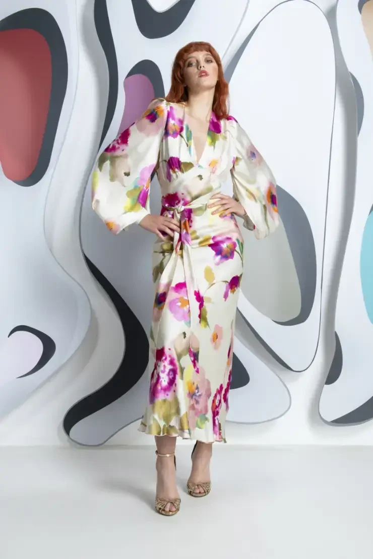 A model poses in a floral-patterned dress against a colorful abstract background.